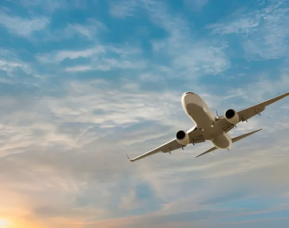 Commercial airplane taking off against a beautiful sky with soft clouds and a sunset in the background, representing air travel